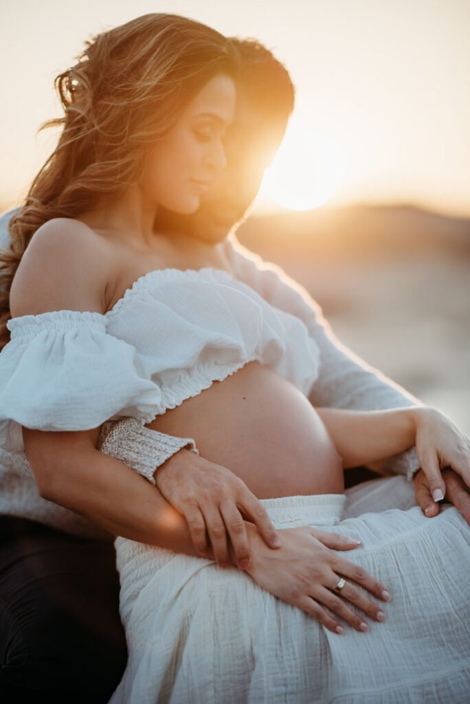 Couple cuddling during a maternity photoshoot on Wingearsheek Beach on the North Shore of Boston, MA