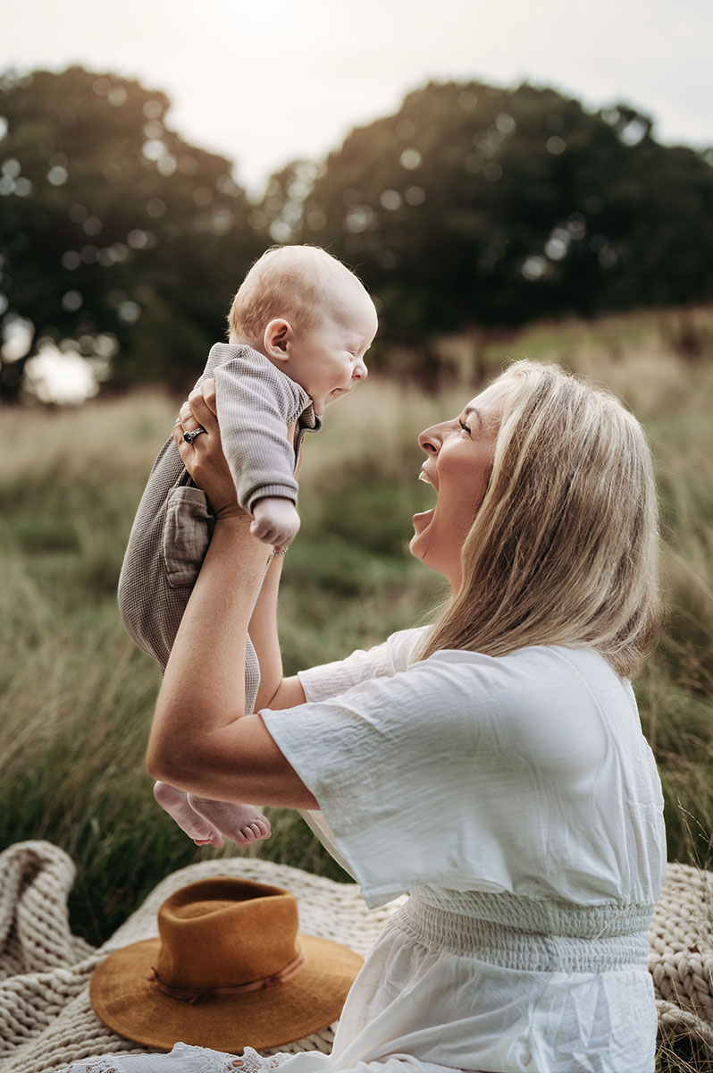 Mom playing with her 3-month old newborn at a family photoshoot south of Boston in Hingham, MA