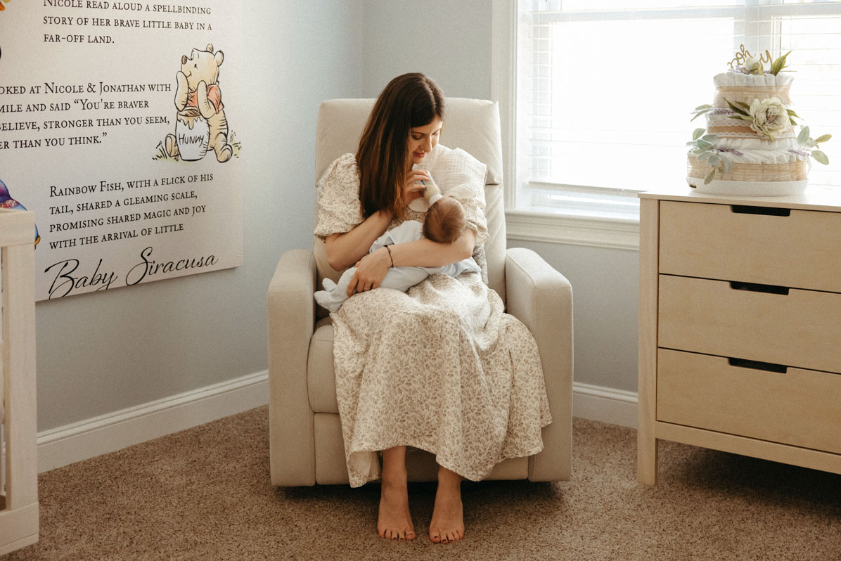 Boston + Cape Cod Newborn Photographer photo of a mom in a rocking chair feeding her newborn by Caryn Scanlan