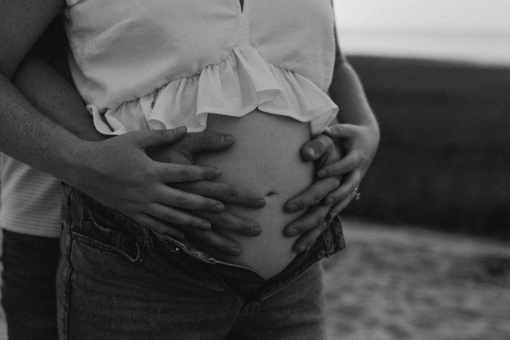 Boston + Cape Cod maternity photography photo of a husband's hands on a mama's belly and her hands entwined with his