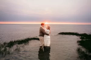 Brewster MA Maternity Session photo of a pregnant mama standing in a tide pool with her husband at sunset as they embrace