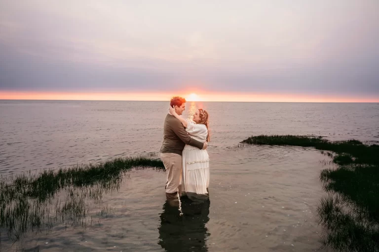 Brewster MA Maternity Session photo of a pregnant mama standing in a tide pool with her husband at sunset as they embrace