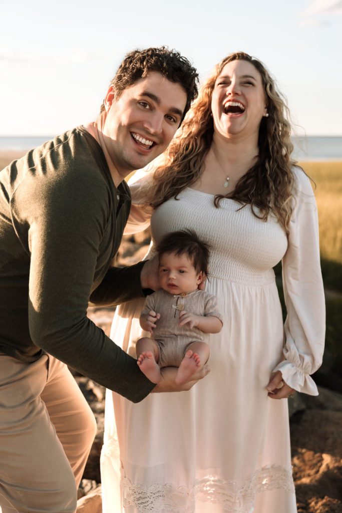 Brewster MA Newborn Beach Session | Brianna, Tyler & Baby Graham 6 Brewster MA Newborn Beach Session photo of a dad being goofy holding his newborn at the mama's belly, where he spent 9 months