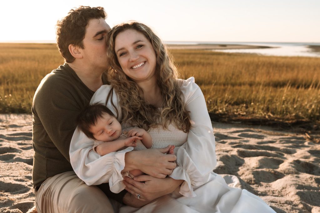 Brewster MA Newborn Beach Session | Brianna, Tyler & Baby Graham 20 brewster newborn photographer photo of a family cradling their newborn sitting on a sandy beach in front of the brewster flats