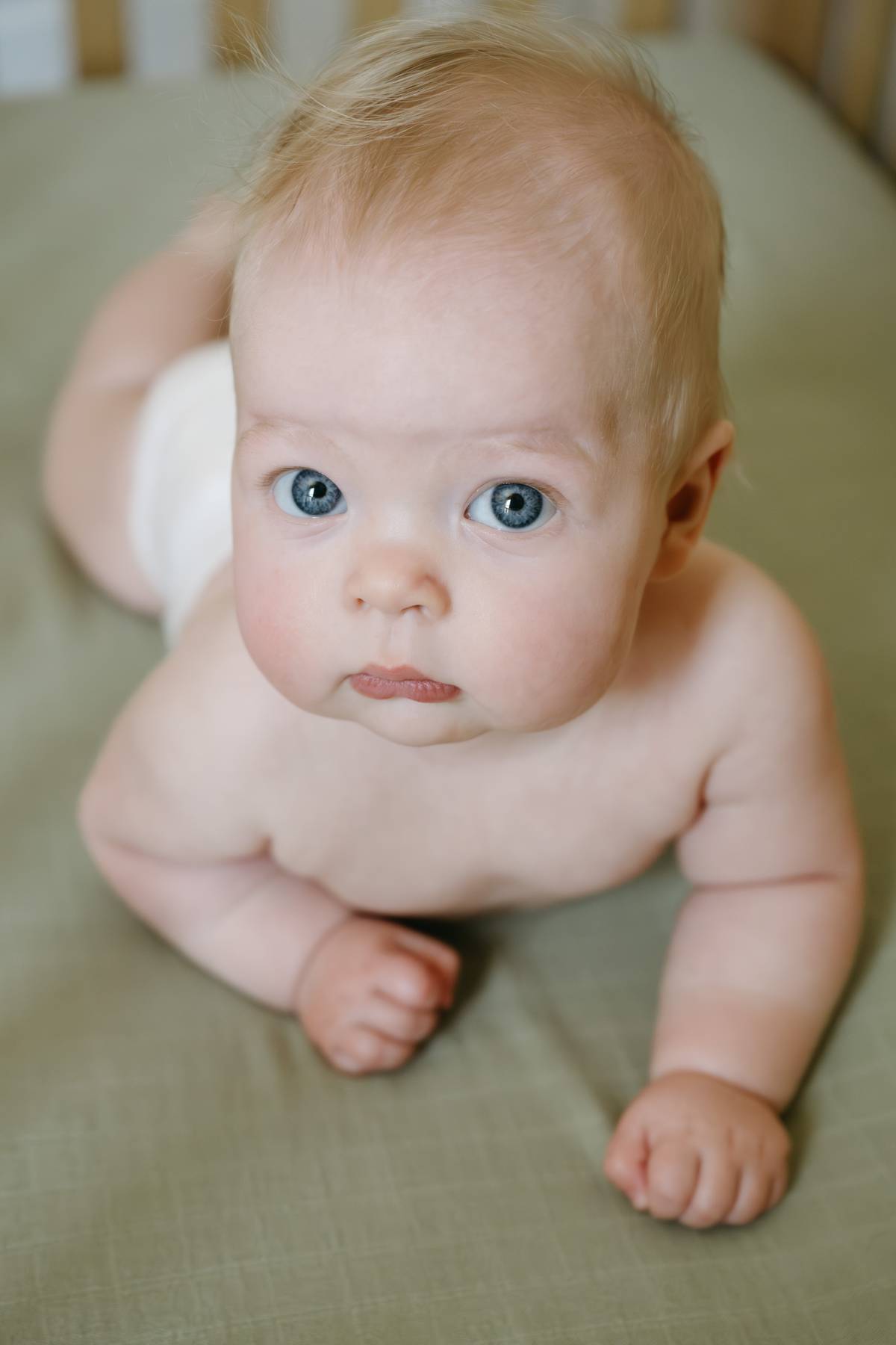 6 month old baby session on the South Shore MA in his crib, on his belly looking up at me