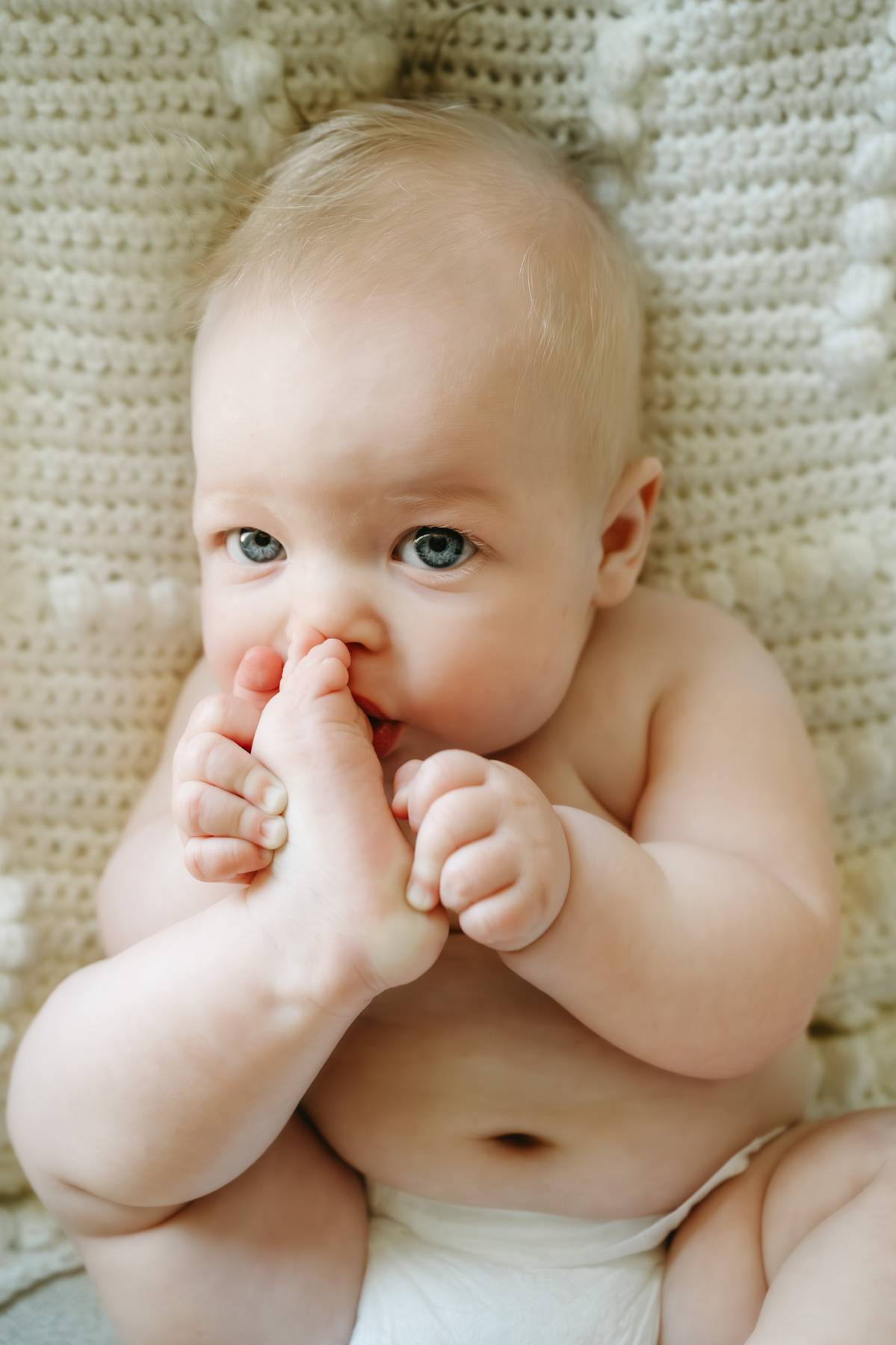 6 month old baby session on the South Shore MA cuddling with his parents sucking his toe